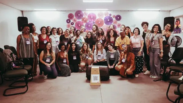 Foto de grupo do encontro em Belo Horizonte, diante da parede de leques roxos