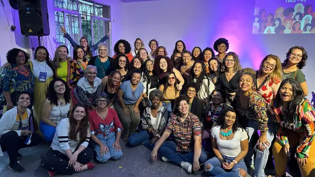 Foto de grupo do primeiro encontro presencial, no Rio de Janeiro, sob luz roxa